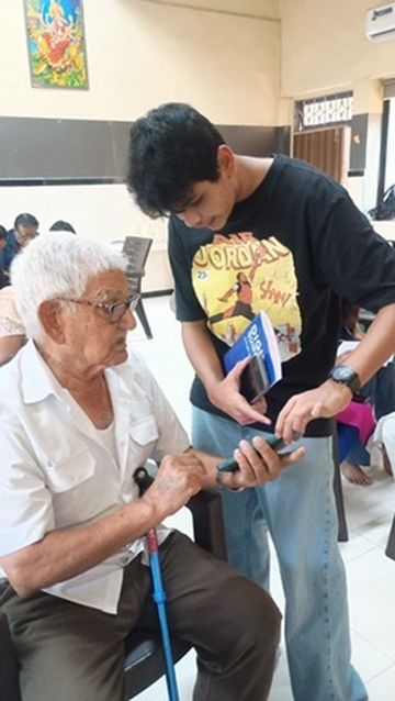 Male volunteer helping an elderly man use a smartphone